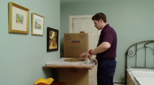 Arpin of RI packer in a bedroom carefully wrapping framed pictures