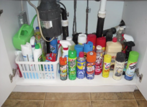 Various household chemicals and cleaning supplies under a kitchen sink cabinet