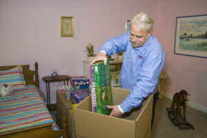 Arpin of RI packer standing in a child's bed room carefully packing board games into a 4.5 cube box