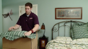 Arpin of RI packer in a bedroom packing up the last minute items of pillows and bedding