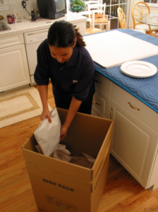 Arpin of RI packer in a kitchen carefully packing up the last minute items of plates and dishes