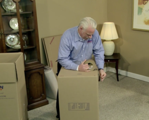 Arpin of RI packer in a dining room setting up the base table of his wrapping station using a sturdy carton