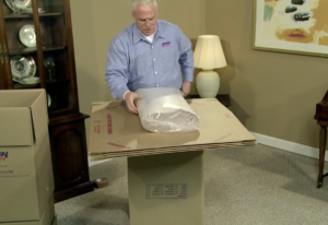 Arpin of RI packer in a dining room laying a bundle of white newspaper onto the working surface of his wrapping station