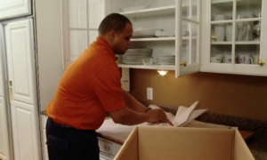 Arpin of RI packer in a kitchen wrapping items in white newspaper on a properly located wrapping station