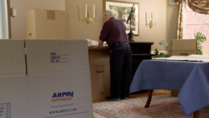 Arpin of RI packer in a dining room packing the contents of the furniture directly. 