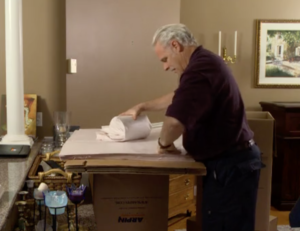 Arpin of RI packer in a dining room wrapping a cylindrical vase with a third layer of paper.