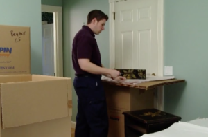Arpin of RI packer removing the drawer from a night stand and packing it in a carton.